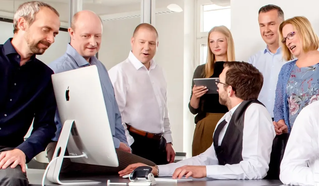 Team im Büro bespricht Projekt am Computer, Zusammenarbeit und Meeting