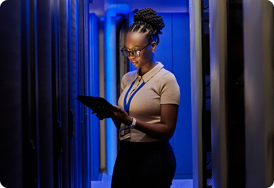 IT-Technikerin mit Tablet im Rechenzentrum zwischen Server-Racks