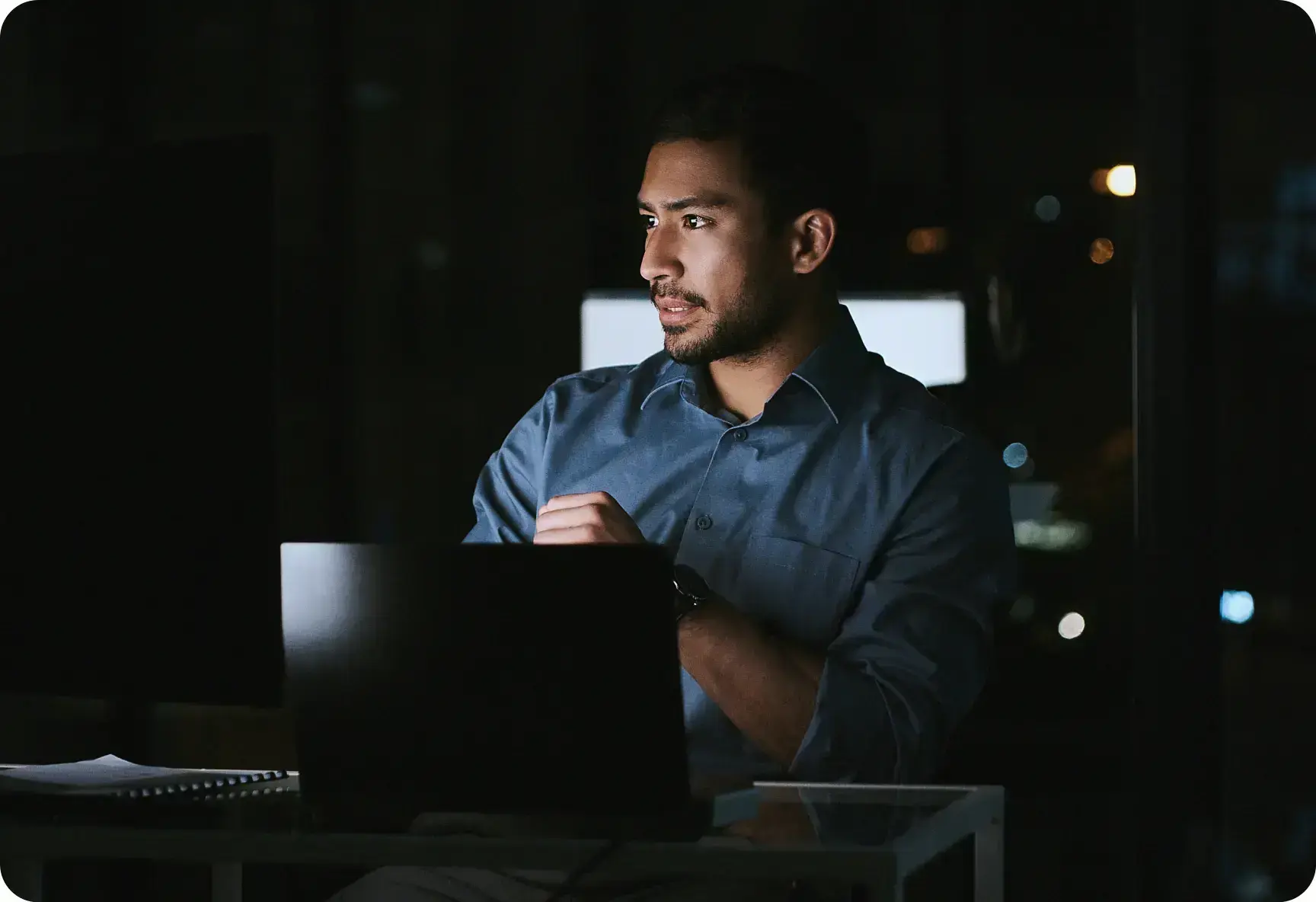 Mann arbeitet nachts am Laptop im Büro, konzentrierte Business-Analyse am PC